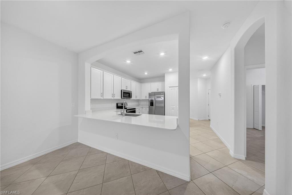 2224 Dragonfruit Way Naples, FL 34120 - Photo 5 of 33 Kitchen with arched walkways, white cabinetry, stainless steel appliances, a peninsula, and recessed lighting