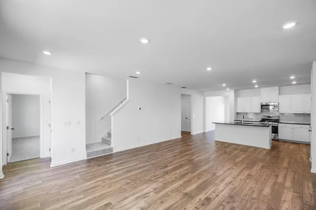a view of kitchen with kitchen island wooden floor center island and stainless steel appliances