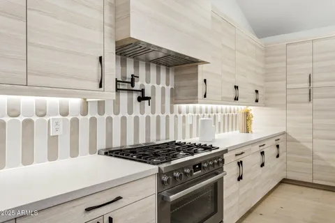 a kitchen with a stove a sink a counter top space and living room view