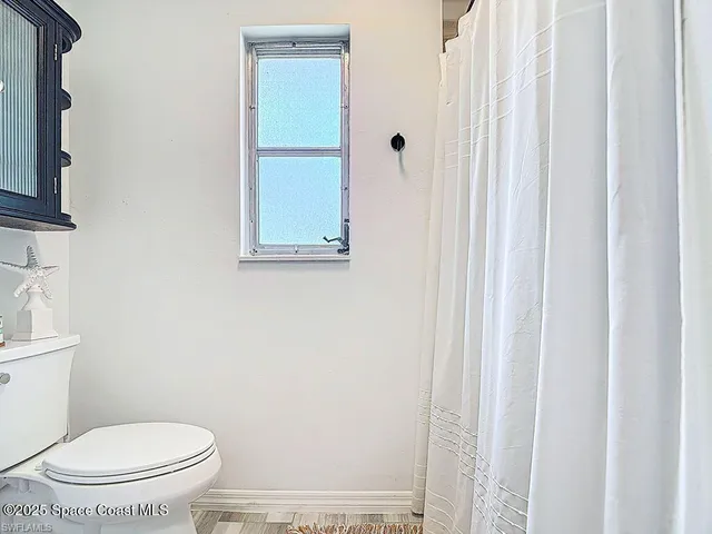 a white toilet sitting next to a shower curtain