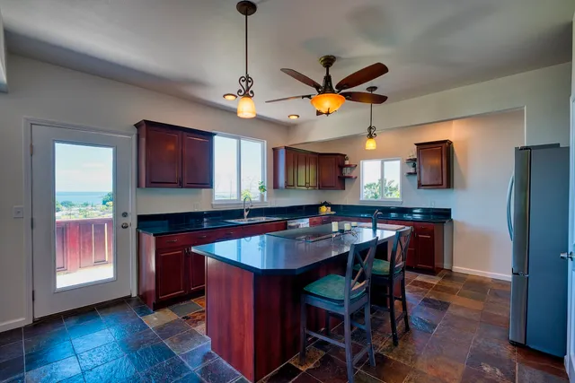 a kitchen with stainless steel appliances granite countertop a sink a stove a dining table and chairs with wooden floor