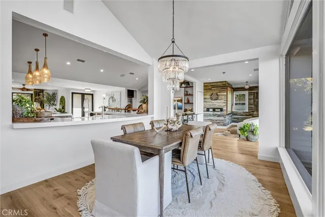 a dining room with wooden floor a chandelier a wooden table and chairs