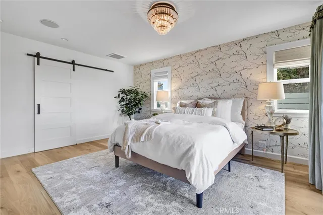 a bed sitting in a spacious bedroom next to a window and a table