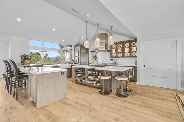 a kitchen with stainless steel appliances kitchen island granite countertop a table chairs sink and cabinets