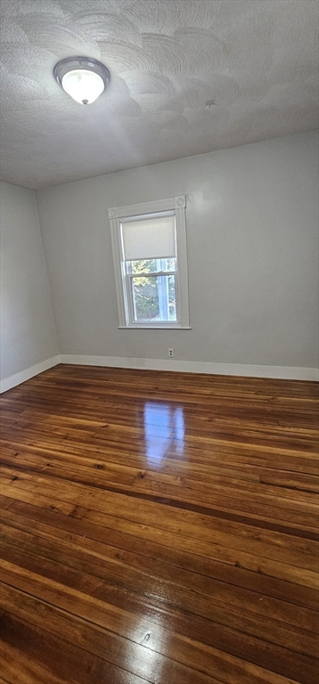 169 Colburn Street, Unit 1 Dedham, MA 02026 - Photo 8 of 12 an empty room with wooden floor and windows