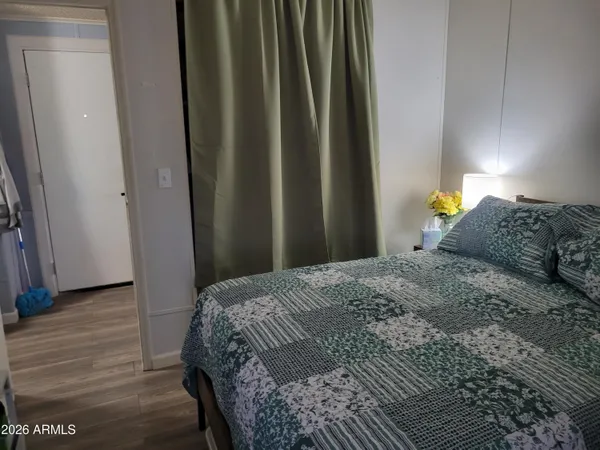 a bedroom with a bed a window and wooden floor