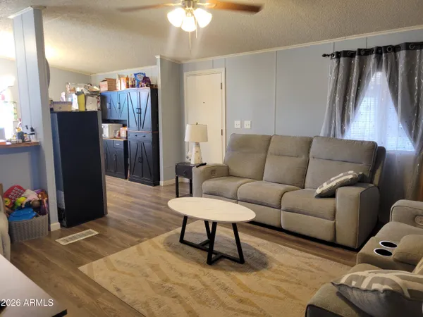a living room with furniture a flat screen tv and a refrigerator