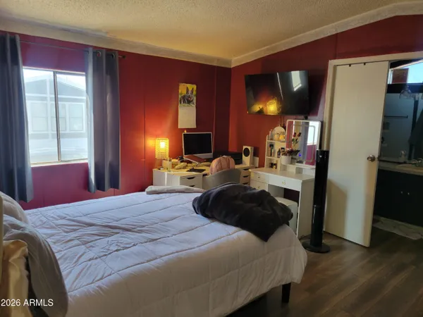 a bedroom with a bed a dresser and flat screen tv