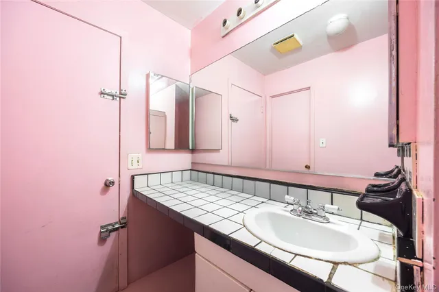 a bathroom with a granite countertop sink a mirror and shower
