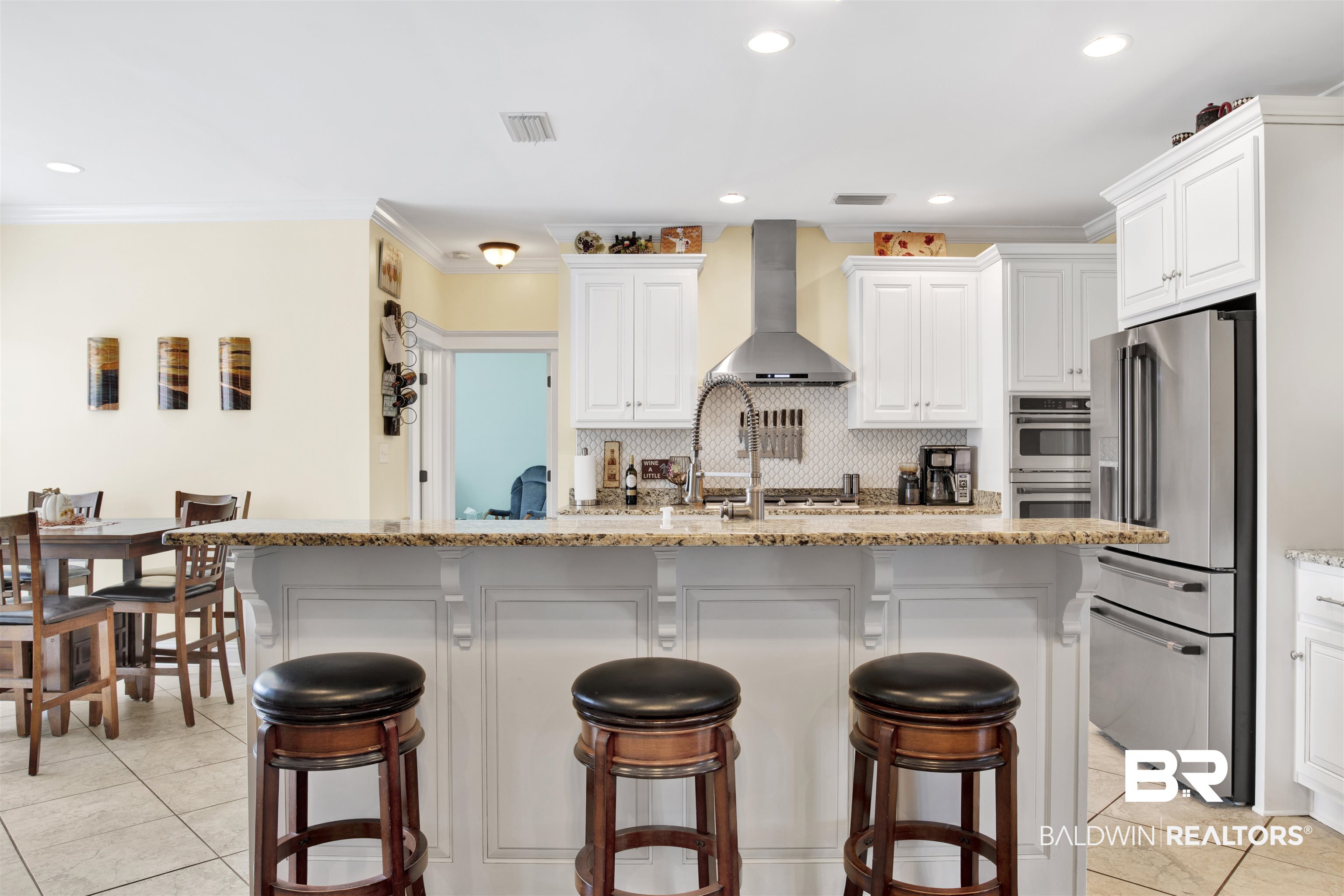 12418 Cambron Trail Daphne, AL 36527 - Photo 21 of 44 Kitchen with wall chimney range hood, white cabinets, appliances with stainless steel finishes, and a breakfast bar area