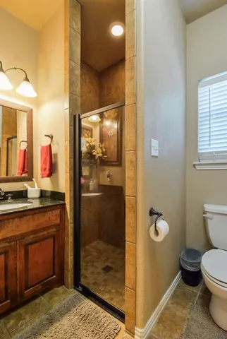 a bathroom with a granite countertop sink a toilet a mirror and shower