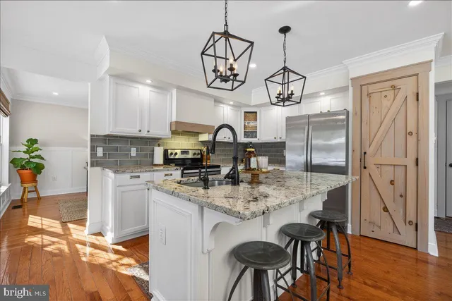 a kitchen with stainless steel appliances granite countertop a sink a stove a refrigerator cabinets and chairs