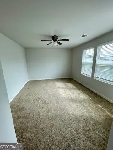 an empty room with a ceiling fan and window