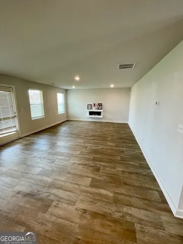 a view of an empty room with window and wooden floor