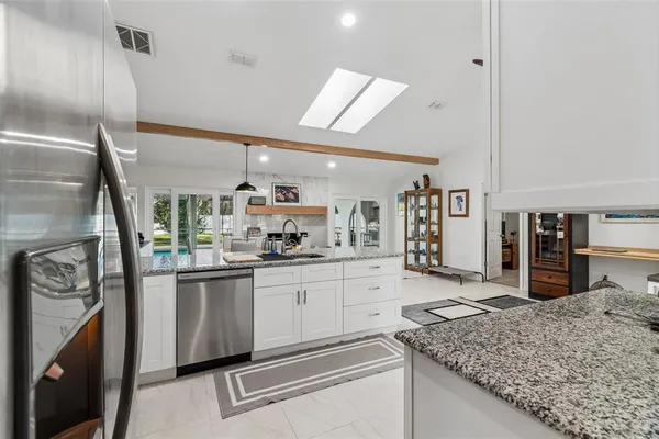 a kitchen with granite countertop a sink stainless steel appliances and white cabinets