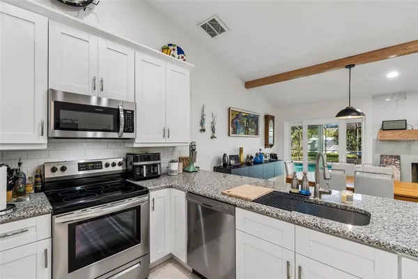 a kitchen with granite countertop white cabinets and stainless steel appliances