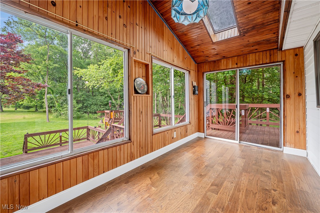 12358 Harmon Road New Springfield, OH 44443 - Photo 36 of 44 Unfurnished sunroom featuring lofted ceiling, a skylight, wood walls, wood finished floors, and wooden ceiling