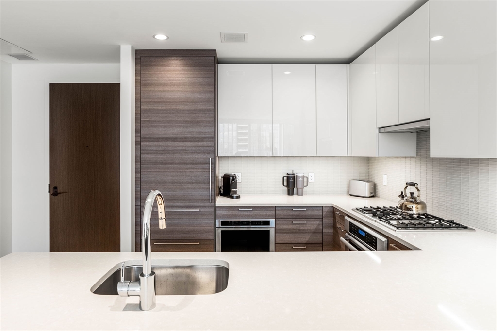 1 Franklin Street, Unit 2609 Boston, MA 02110 - Photo 11 of 24 a kitchen with stainless steel appliances kitchen island granite countertop a sink and cabinets