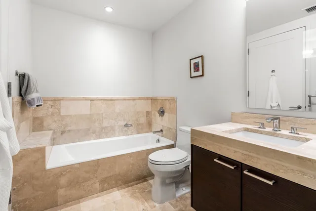 a bathroom with a granite countertop sink a toilet and bathtub
