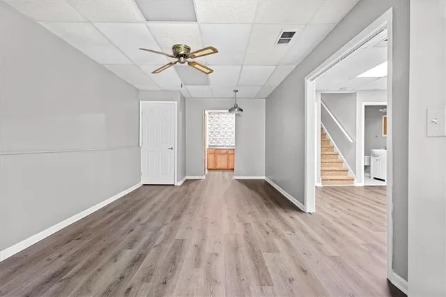 an empty room with wooden floor ceiling fan and windows