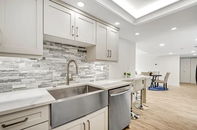 a kitchen with stainless steel appliances a sink a stove and white cabinets with wooden floor