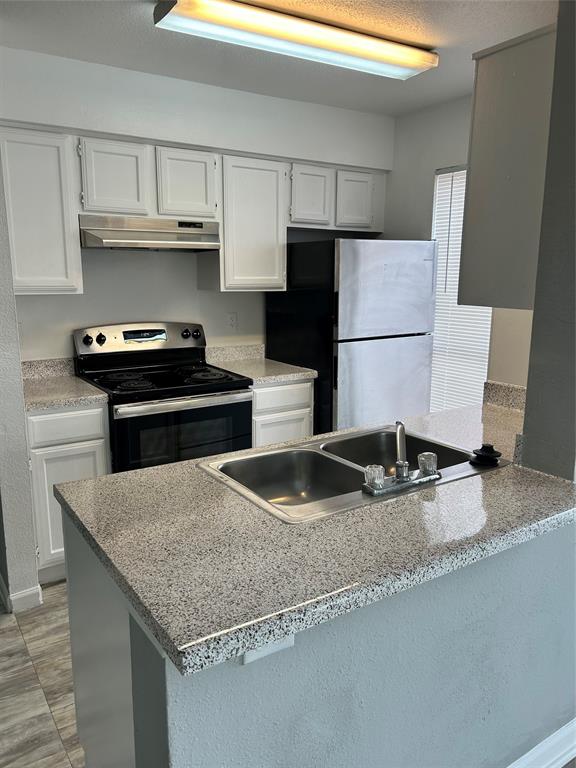 a kitchen with granite countertop a sink a stove and refrigerator