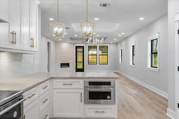 a kitchen with stainless steel appliances kitchen island granite countertop a stove a sink and a white cabinets