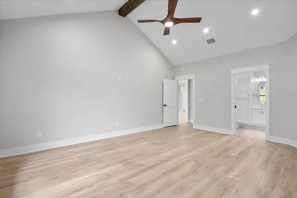 an empty room with wooden floor ceiling fan and windows