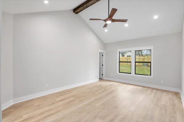 an empty room with wooden floor fan and windows