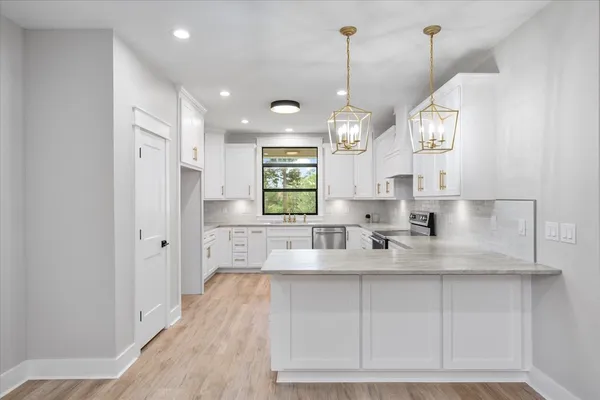 a large kitchen with kitchen island white cabinets and stainless steel appliances