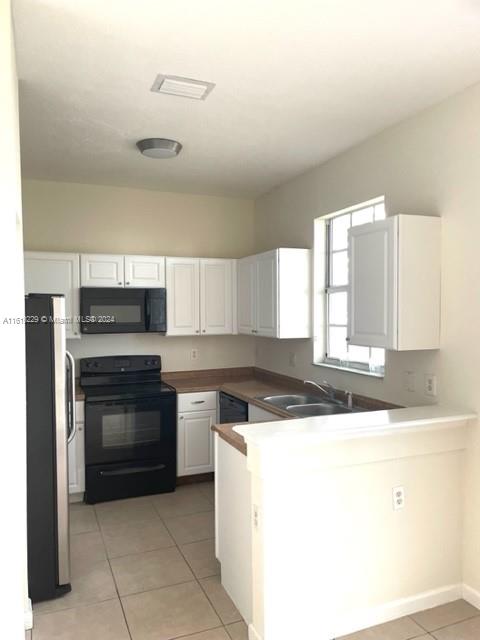 2133 Northeast 7th Street, Unit 2133 Homestead, FL 33033 - Photo 5 of 28 a kitchen with a stove a sink and a microwave