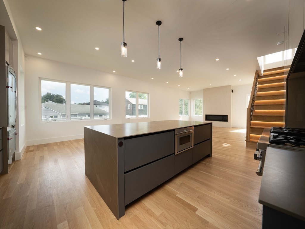 21 Cavanaugh Path Newton, MA 02459 - Photo 4 of 30 a large white kitchen with a large kitchen island wooden floors and stainless steel appliances