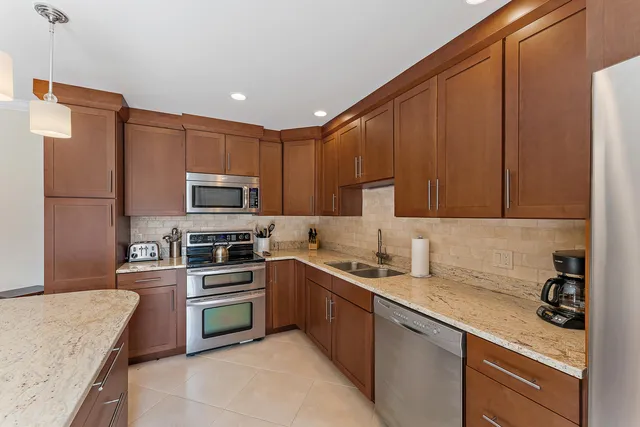 a kitchen with stainless steel appliances granite countertop a sink stove refrigerator and cabinets
