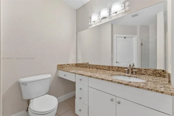 a bathroom with a granite countertop sink vanity mirror and toilet
