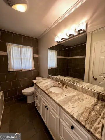 a bathroom with a granite countertop sink a toilet and a mirror