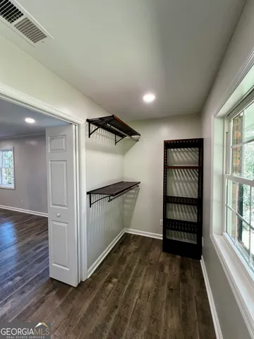 an empty room with wooden floor closet and windows