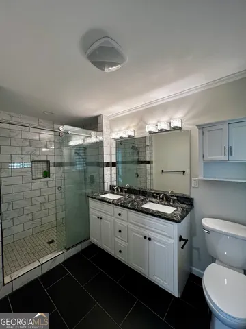 a bathroom with a granite countertop sink a toilet a mirror and shower
