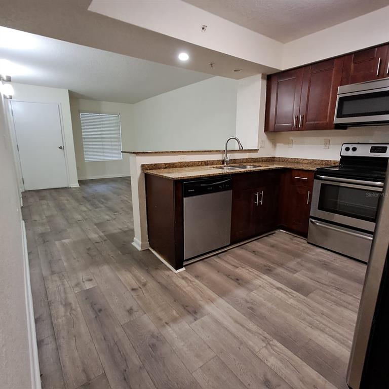 2323 McCoy Road, Unit 711 Orlando, FL 32809 - Photo 2 of 14 a kitchen with granite countertop a stove and a sink