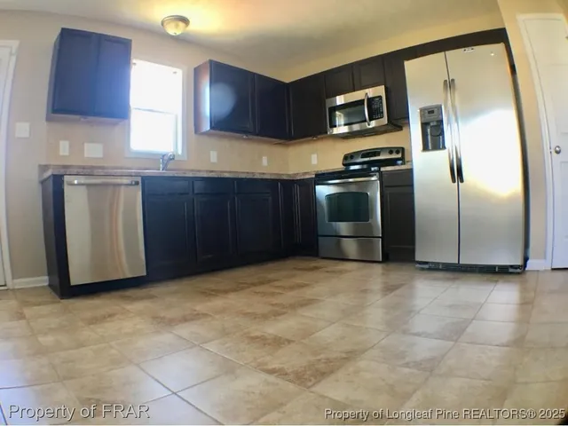 a kitchen with stainless steel appliances granite countertop a refrigerator and a stove top oven