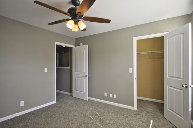an empty room with closet and a chandelier fan