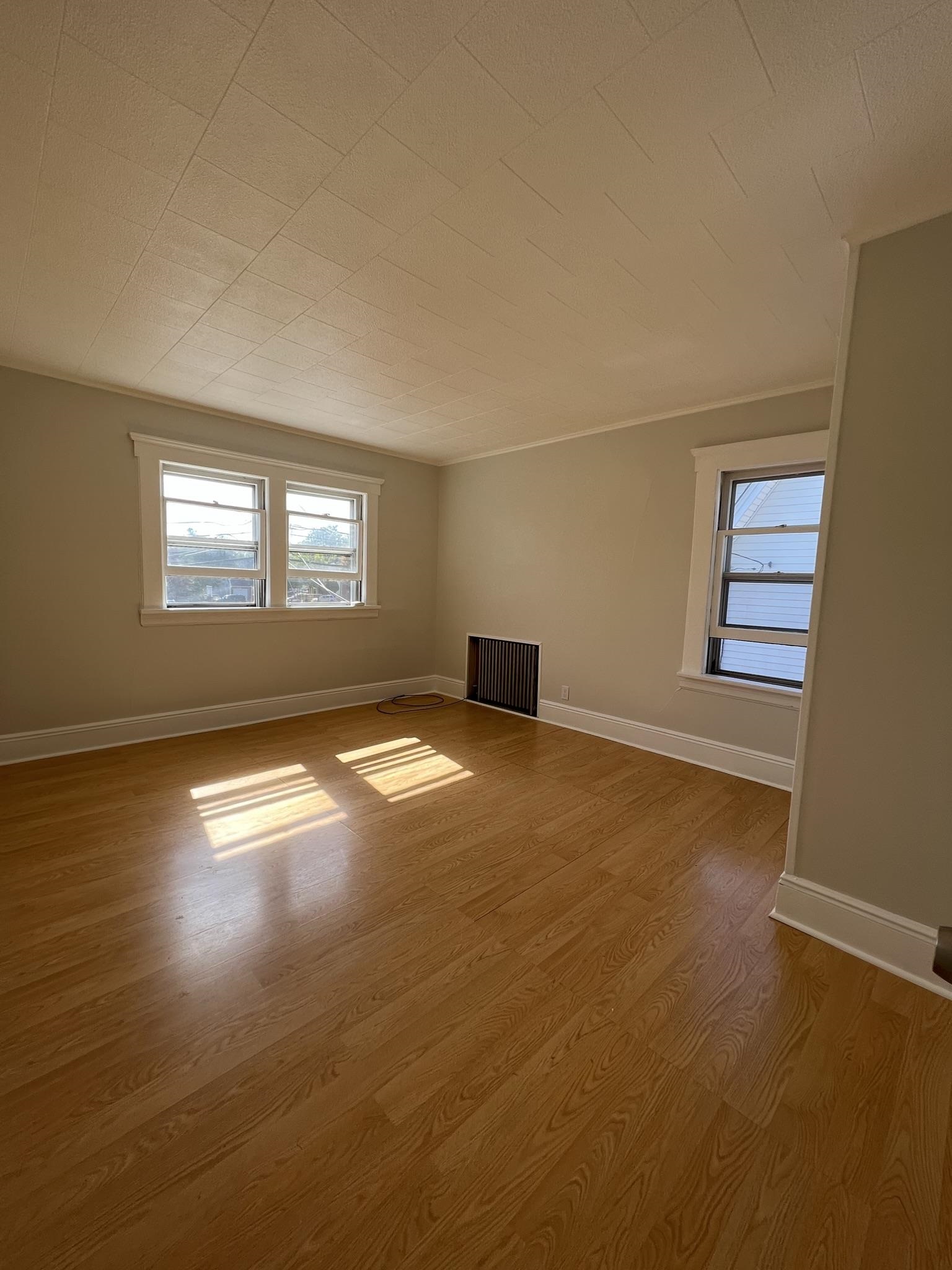 128 Hazelton Street, Unit 2 Ridgefield Park, NJ 07660 - Photo 2 of 6 an empty room with wooden floor and windows