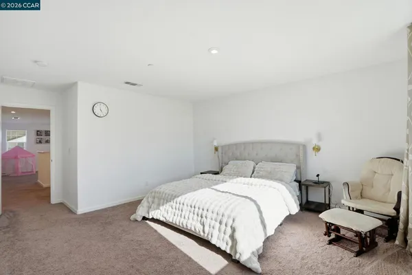 a spacious bedroom with a bed and a chair