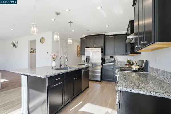 a kitchen with stainless steel appliances granite countertop a sink a stove and a refrigerator