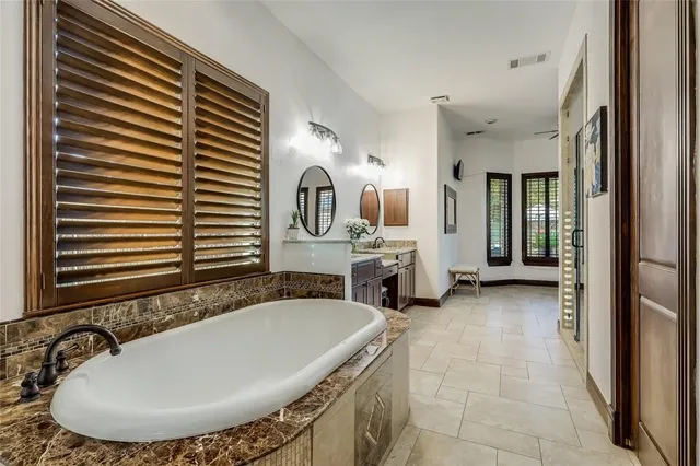 a bathroom with a tub a sink and a mirror