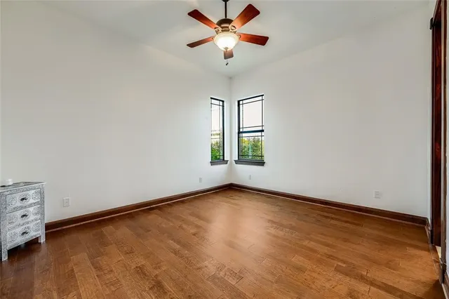 a view of an empty room with window and chandelier fan