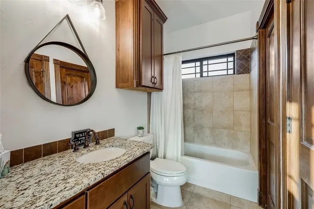 a bathroom with a granite countertop toilet a sink and a mirror
