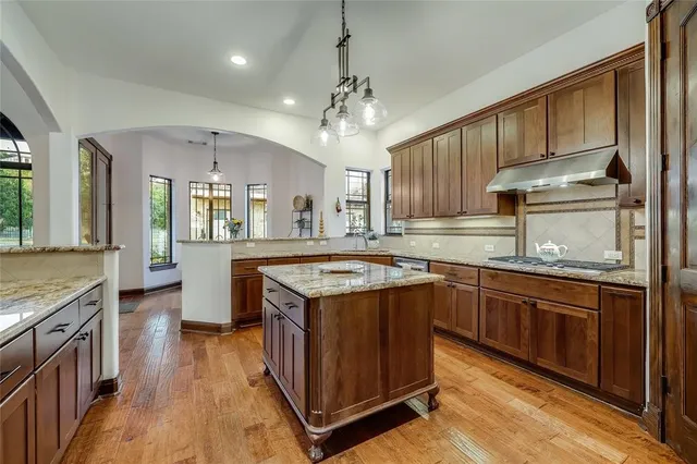 a kitchen with stainless steel appliances granite countertop wooden floors and view of living room