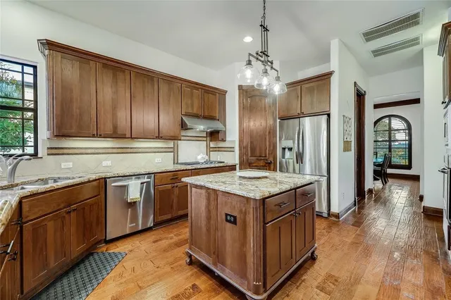 a kitchen with stainless steel appliances granite countertop wooden floors and sink