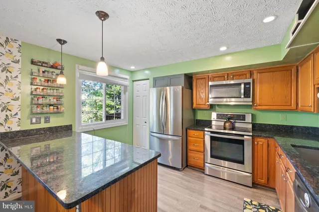a kitchen with stainless steel appliances granite countertop a stove a sink and a refrigerator