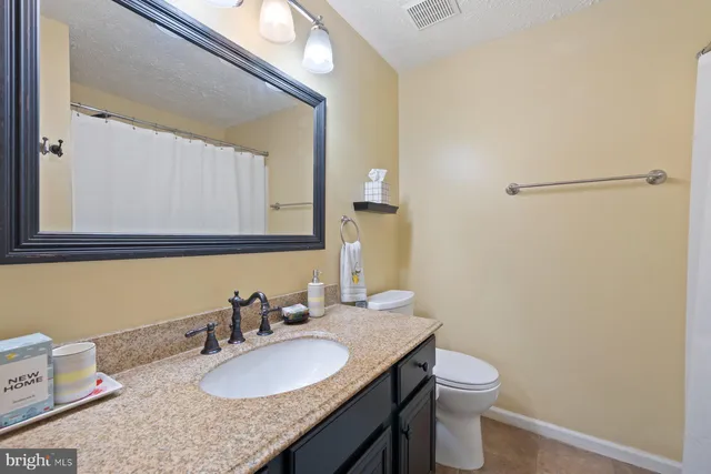 a bathroom with a granite countertop sink toilet and a mirror